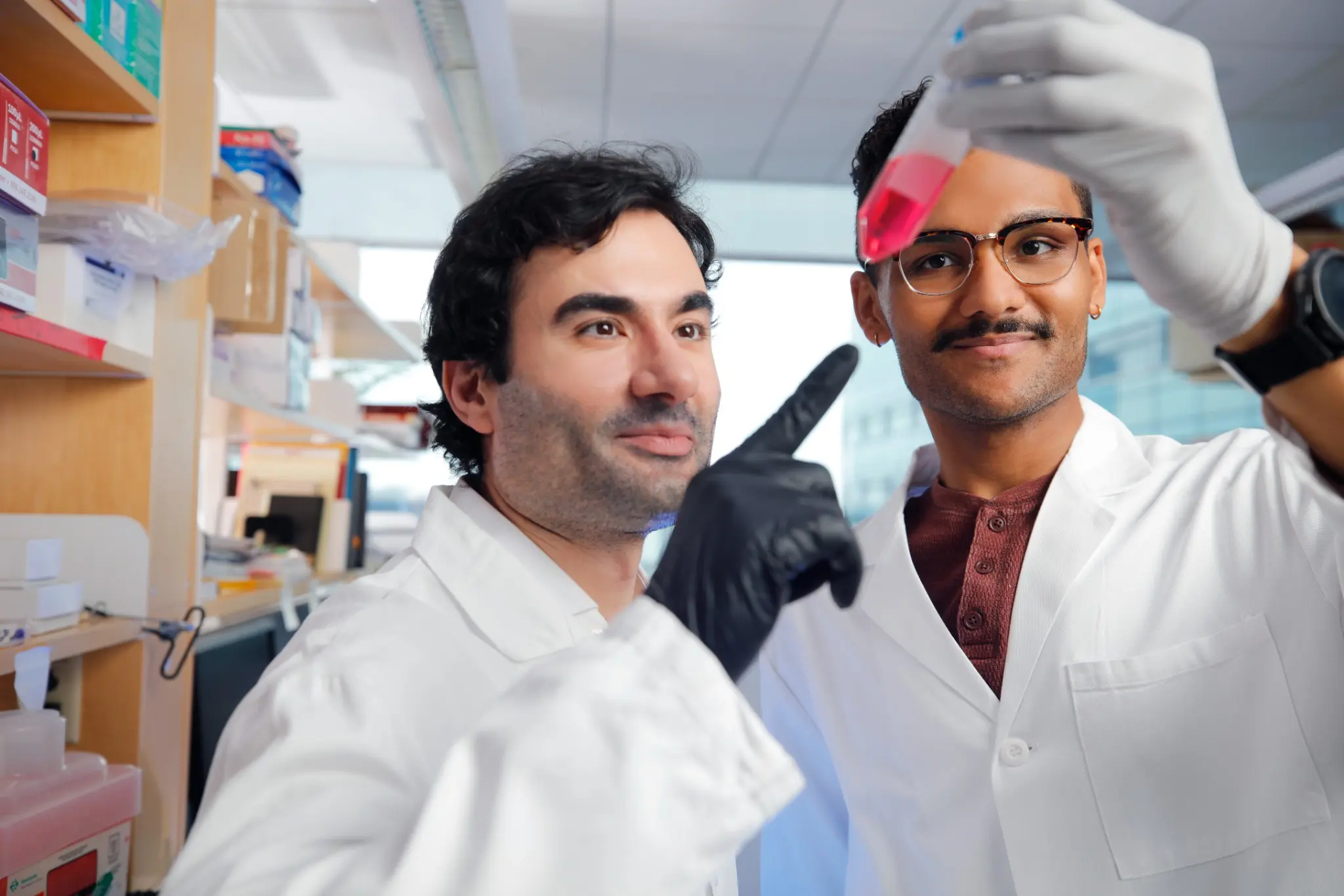 Sahand Hormoz and a lab member discussing a cell culture flask